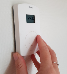 image of fingers on an electric room thermostat